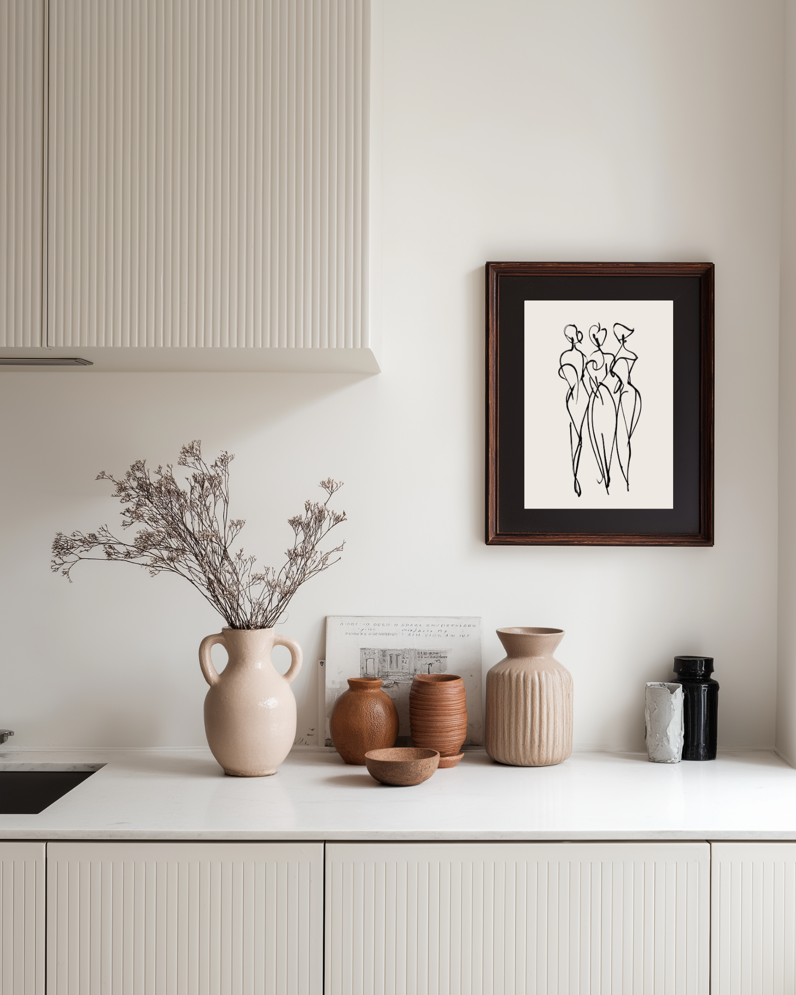 Abstract women wall art above a kitchen counter with decorative vases.