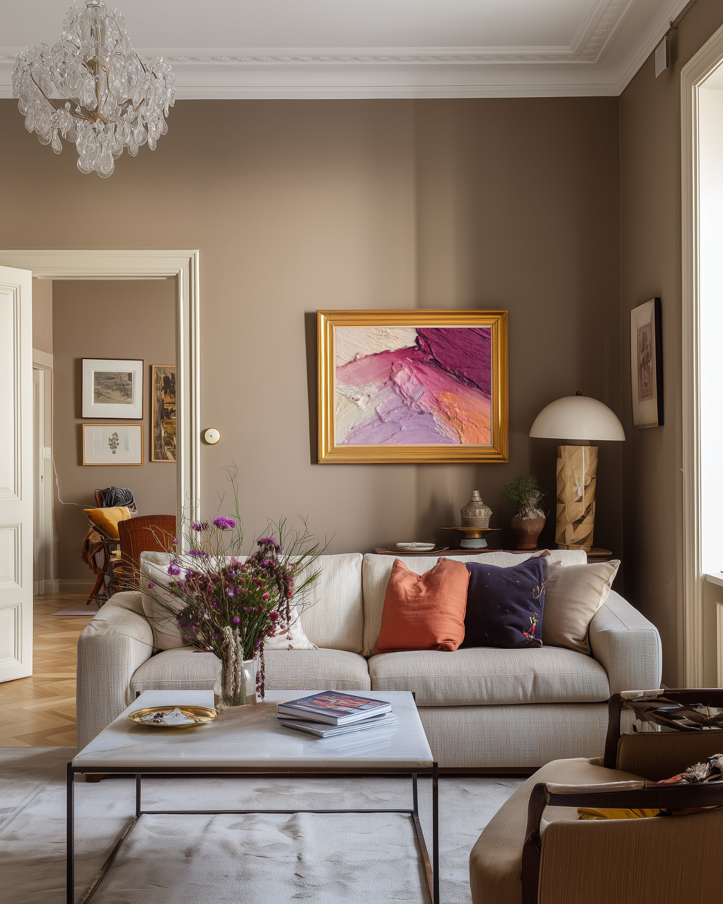 Colorful iving room with beige sofa, colorful pillows, and an abstract pink painting on the wall.