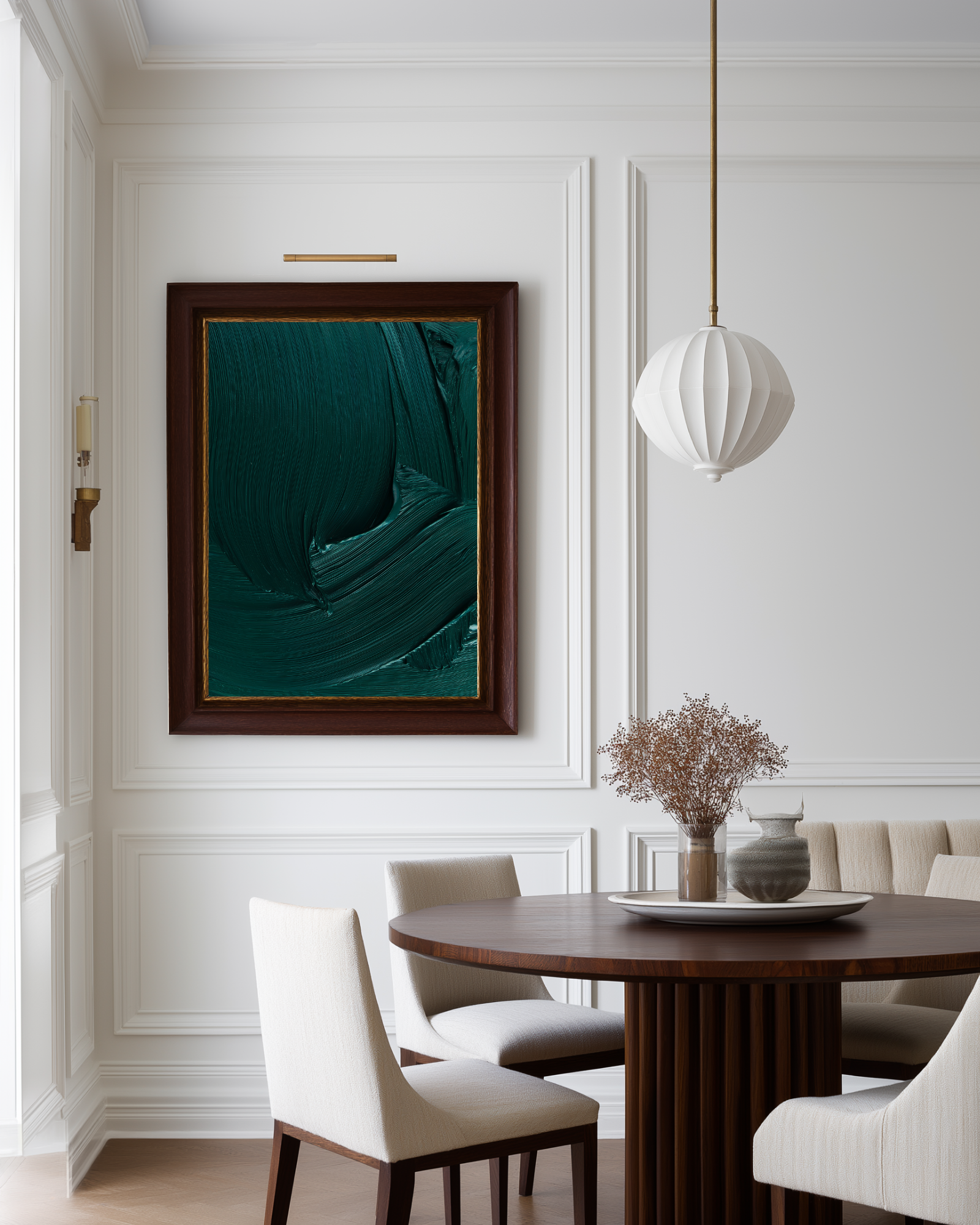 Dining room with a framed abstract dark green paint brush artwork on the wall, a round wooden table, and white chairs.