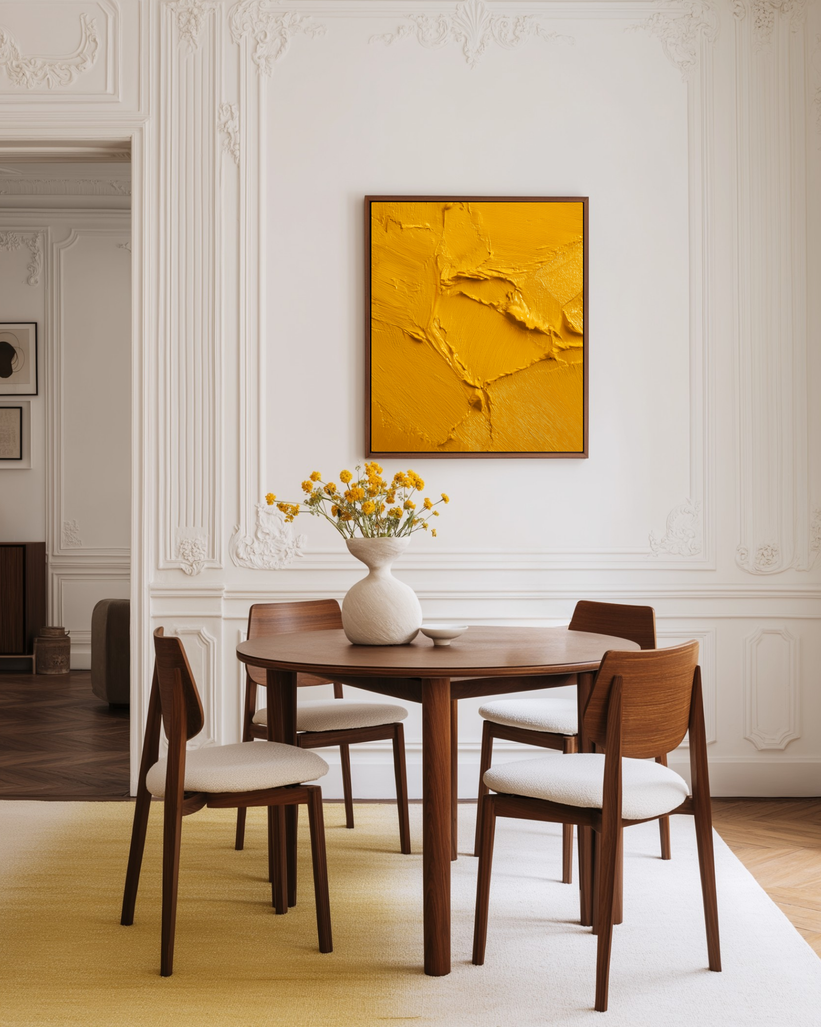 Dining room with wooden table and chairs, white vase with yellow flowers, and abstract orange painting on wall.