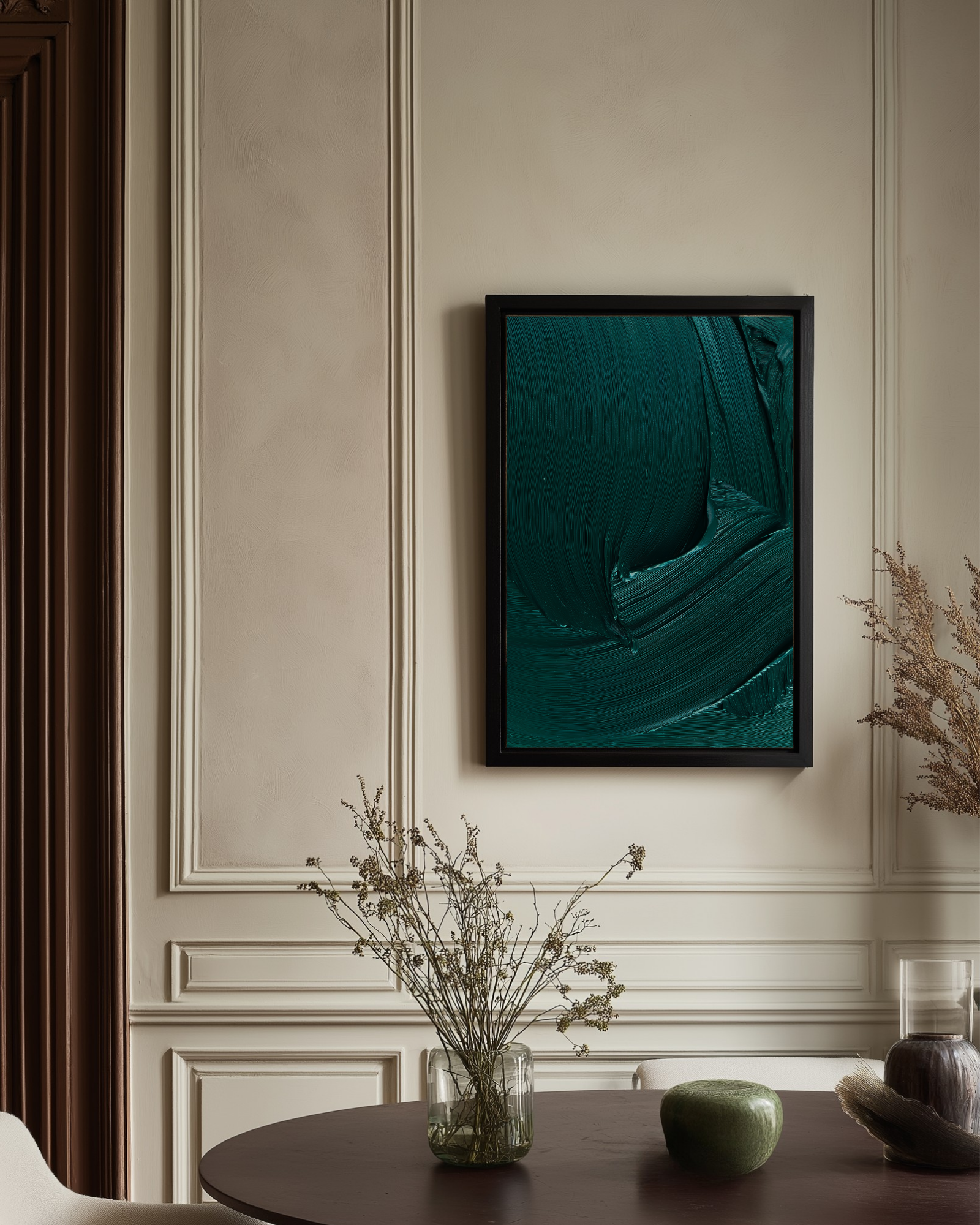 Framed abstract dark green artwork in a room with decorative elements on a table.