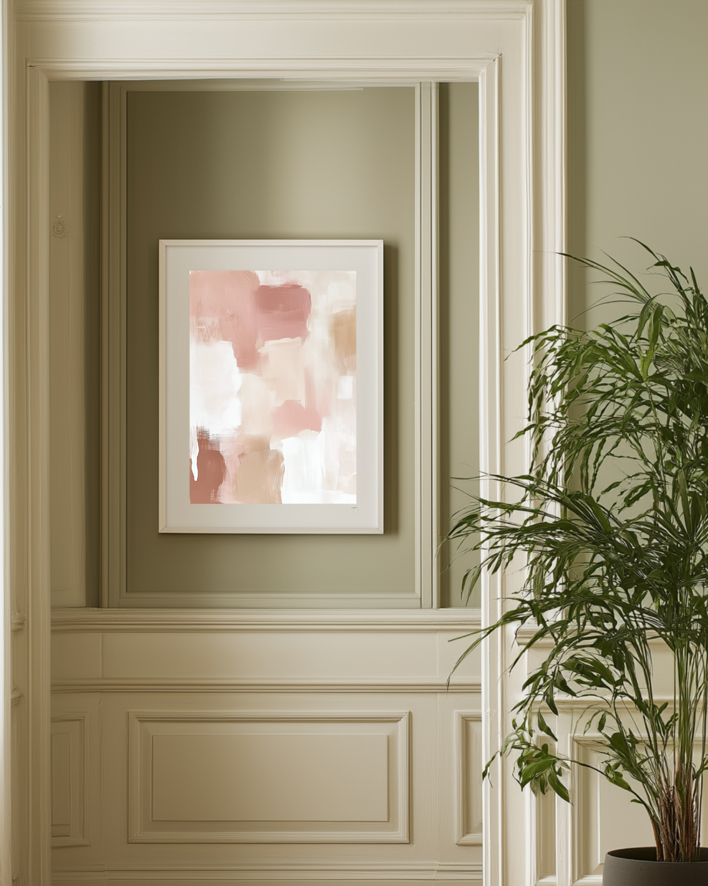 Framed abstract pink and white wall art on a pistachio green wall with a plant in the foreground