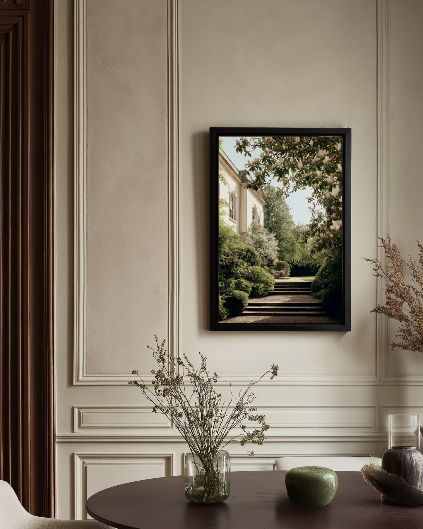 Framed artwork of a garden scene on a wall with decorative elements below.