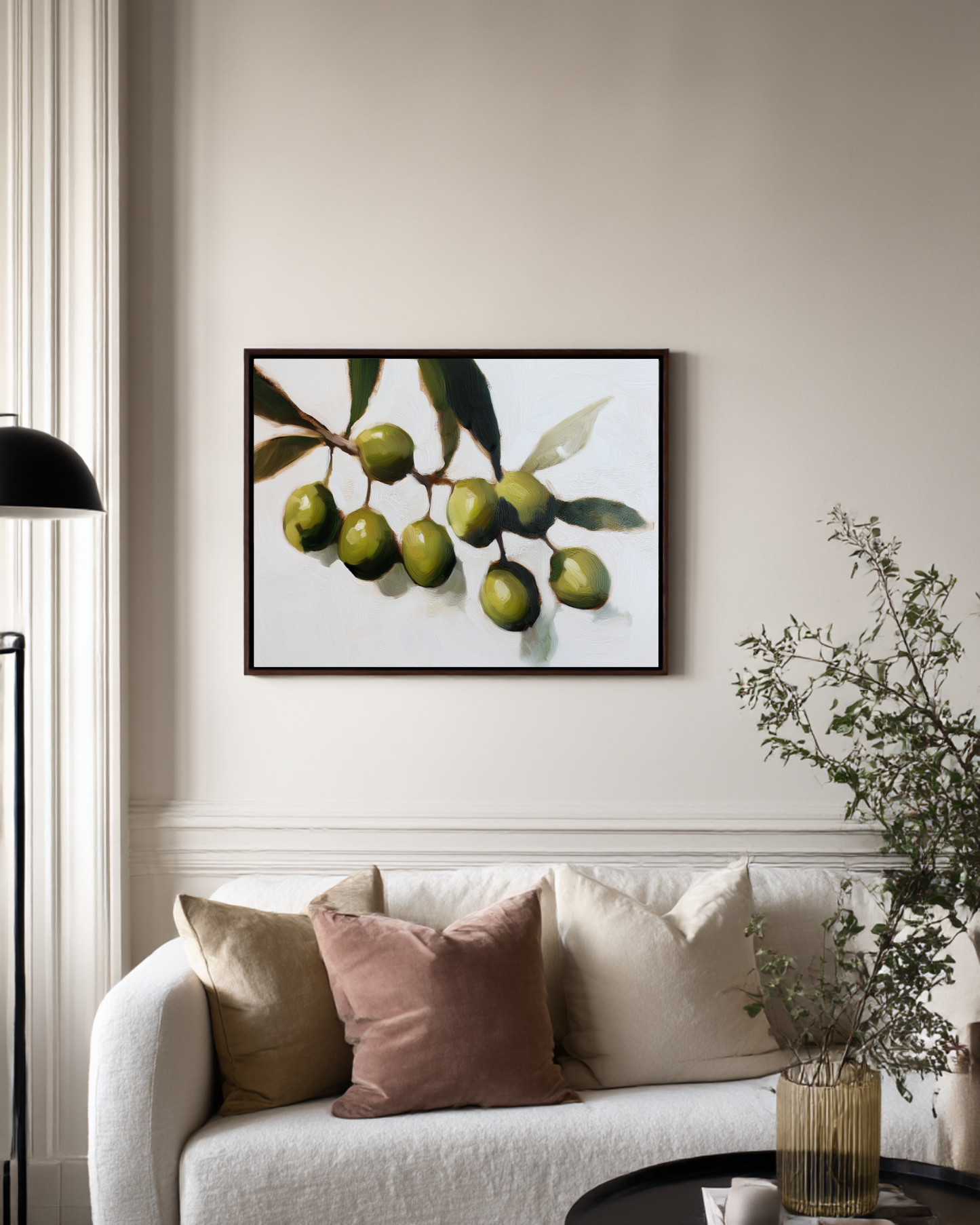 Framed artwork of green olives on a wall above a sofa with decorative pillows.