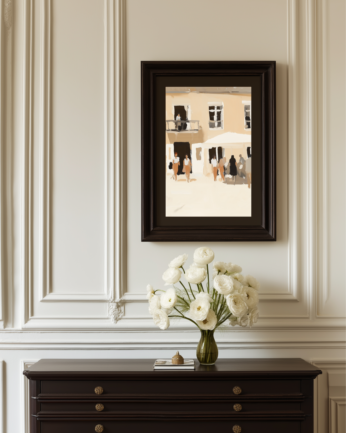 Framed artwork of soft colored beige and white abstract people on a wall above a dark wooden console table with a vase of white flowers.