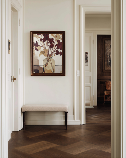 Hallway with a bench and a framed burgundy and beige floral poster on the wall.