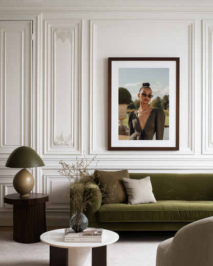 Living room with a green sofa, framed fashion portrait poster on the wall
