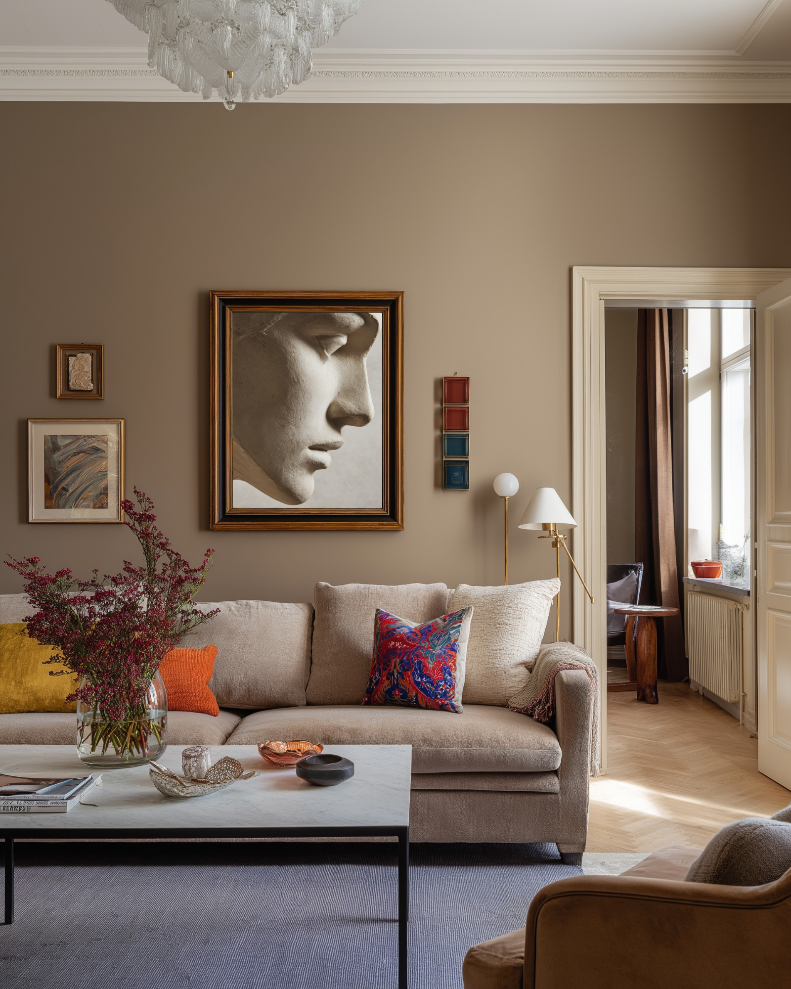 Living room with beige sofa, decorative colorful pillows and beige statue wall art.