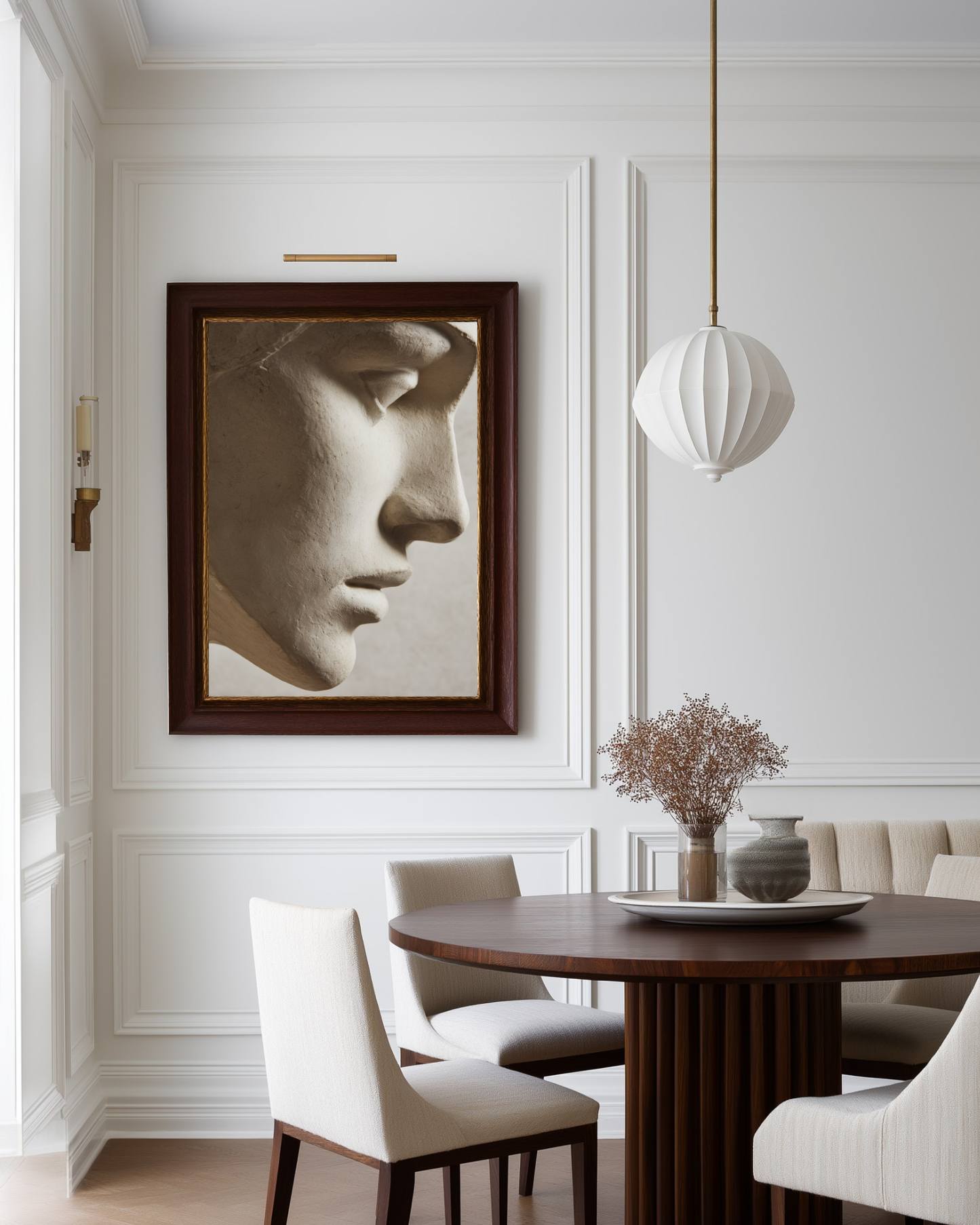 Dining room with a framed sculpture photograph on the wall, wooden table, and white chairs.
