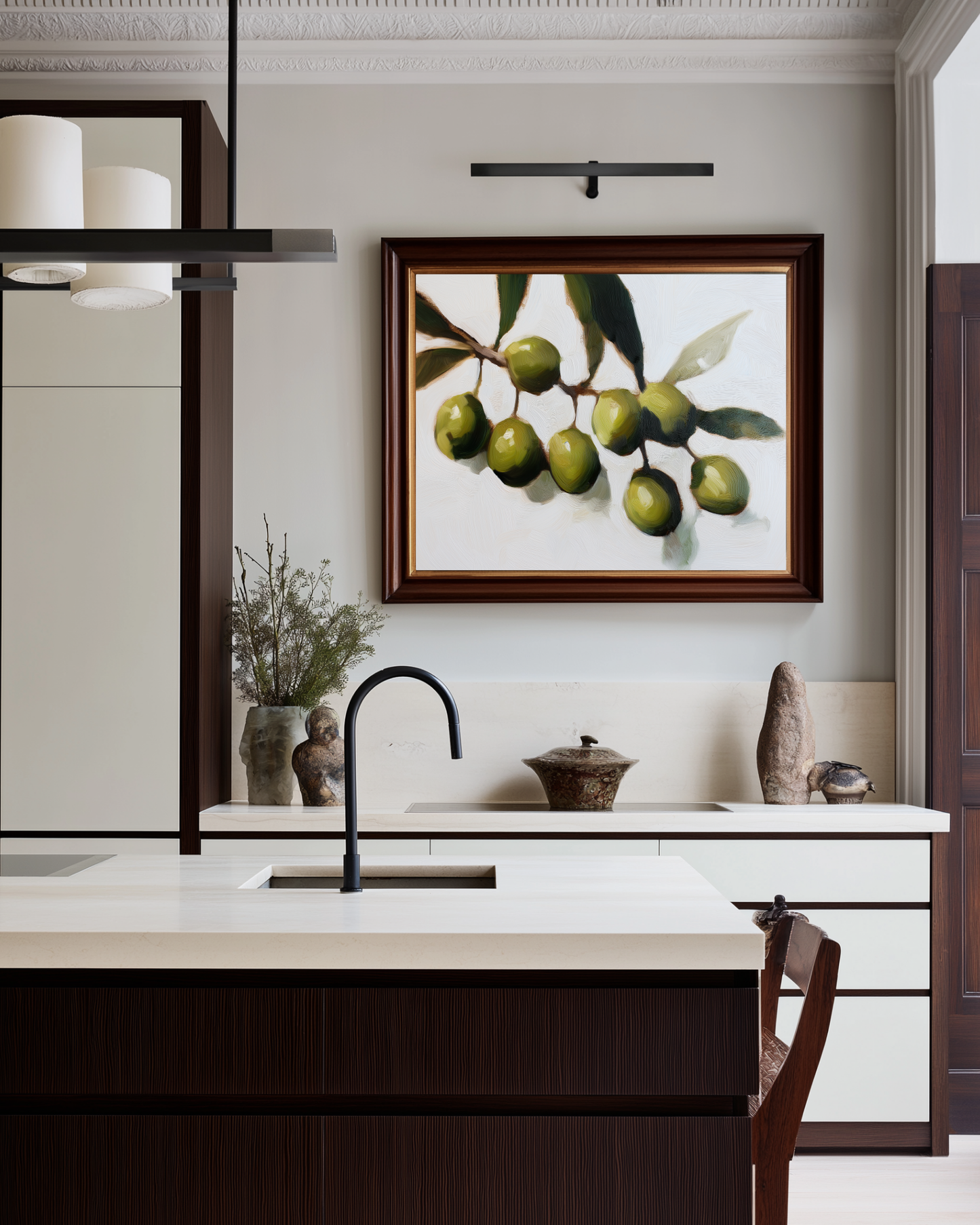Modern kitchen with white island, black faucet, and olive branch artwork on wall.