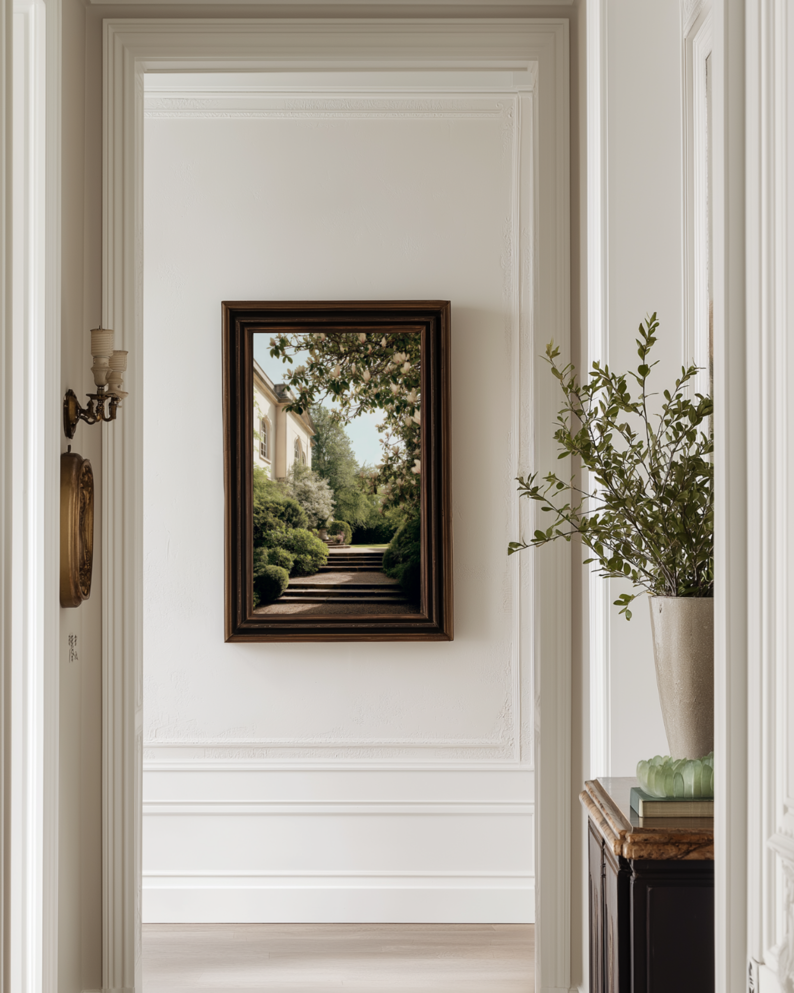 Narrow hallway with a framed vintage photograph poster on the wall, a plant, and a wooden side table.