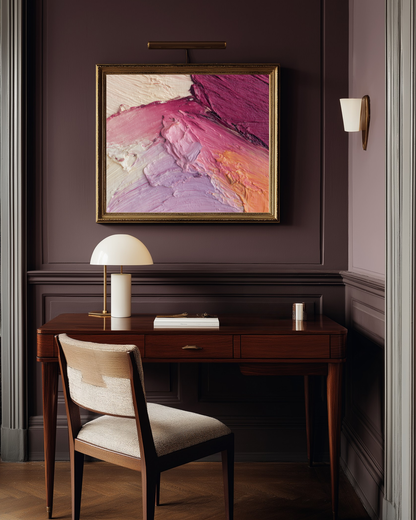 Stylish home office with a wooden desk, chair, and abstract pink and purple makeup art on a purple wall.