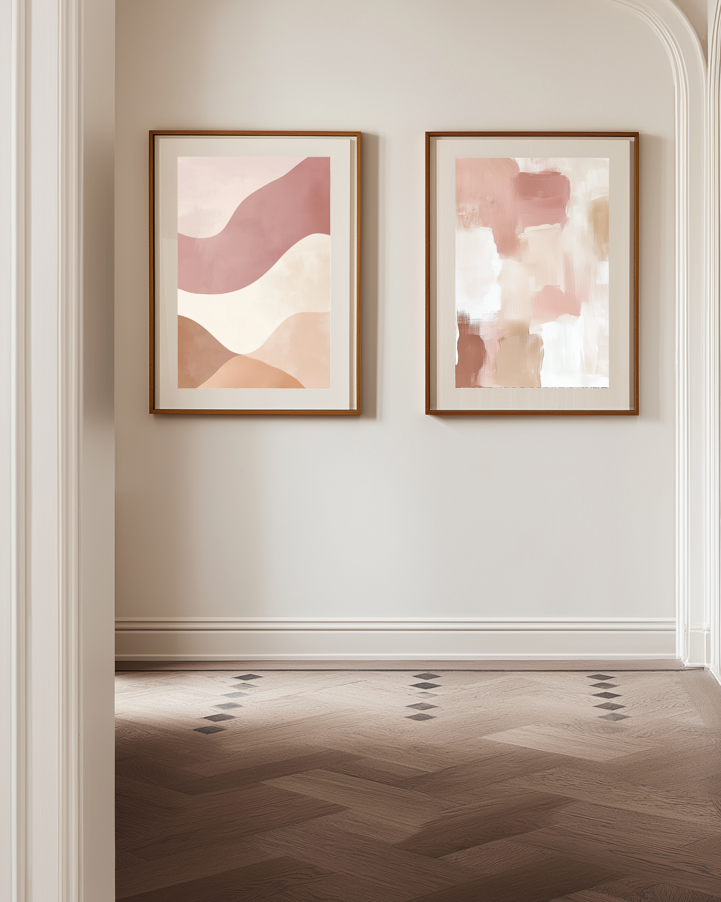 Two abstract pink and beige art pieces in wooden frames on a wall with a wooden floor.