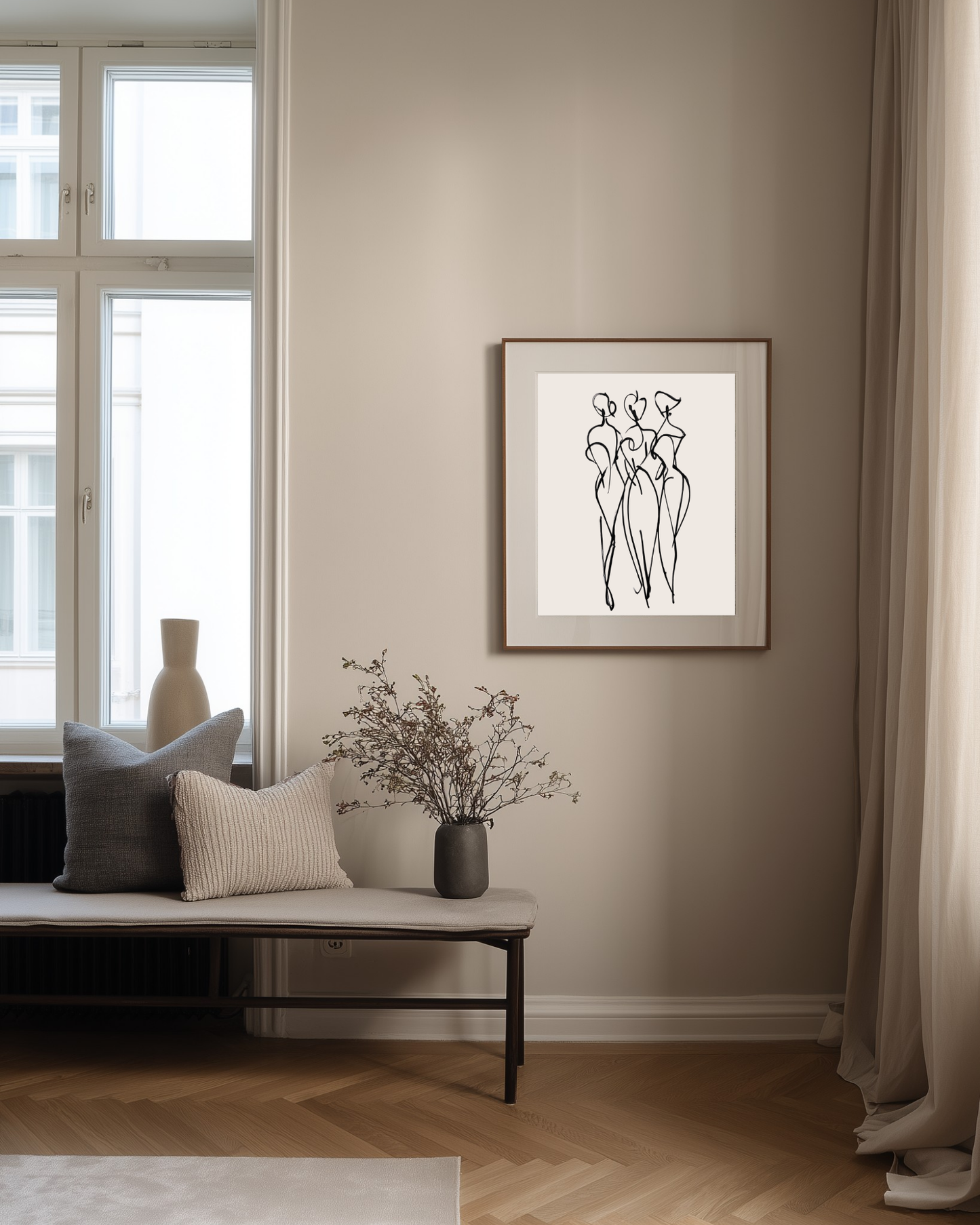 Framed black and white art print on a wall in a living room with a bench and decorative items.
